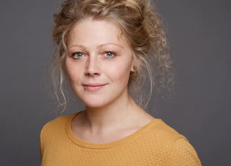 Bewerbungsfotos Dortmund junge Frau mit Ring in der Lippe gelber Pullover vor grau